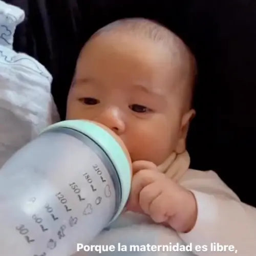Bebé bebiendo de un biberón Happymami menta con marcas de mililitros