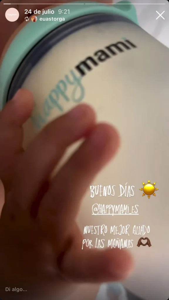 Mano de un bebé sobre un biberón Happymami menta con leche