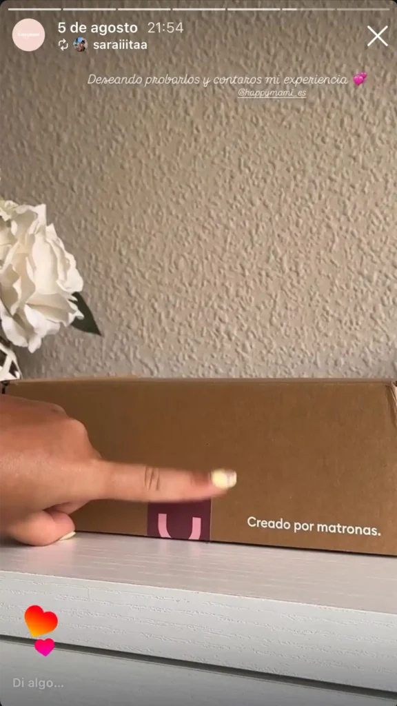 Dedo señalando el texto Creado por matronas en el lateral de una caja de cartón Happymami