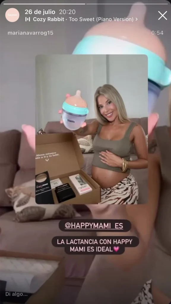 Embarazada sonriente con un biberón Happymami menta y la caja del pack abierta en el sofá