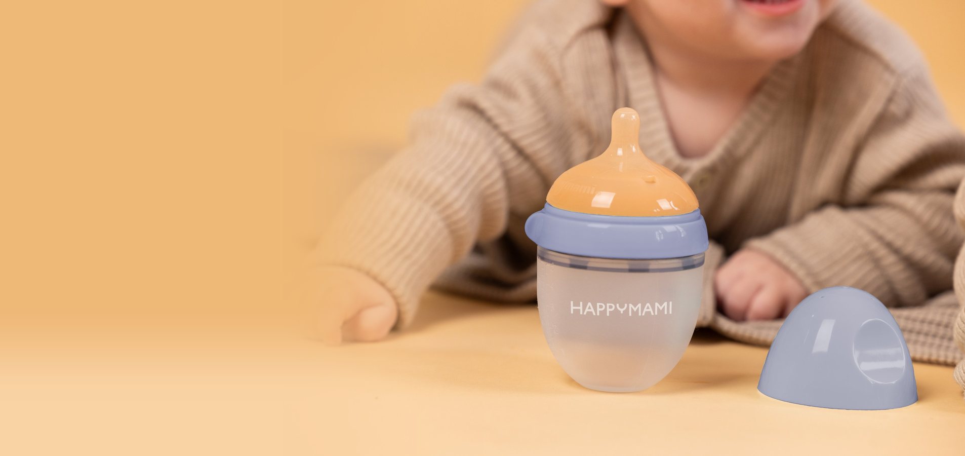Happymami bottle with its cap off and a smiling baby behind it