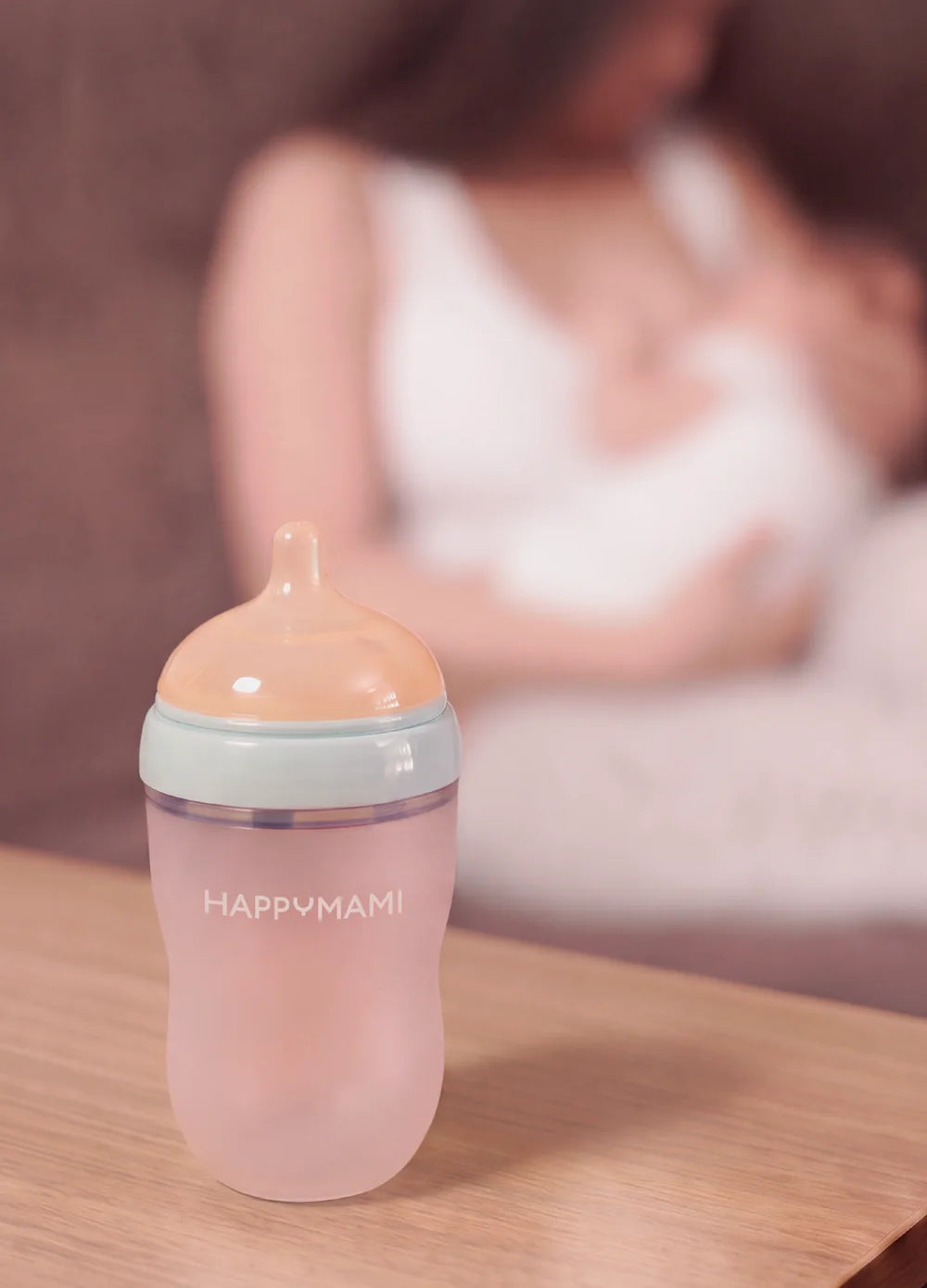 Happymami bottle on the table while mum breastfeeds in the background